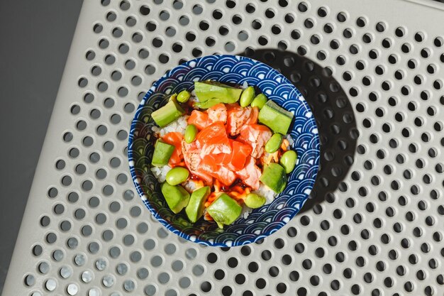 Poke bowl with rice avocado edamame beans and smoked salmon hard light deep shadow