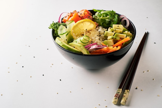 Poke bowl with salmon, avocado, isolated over white background. top view