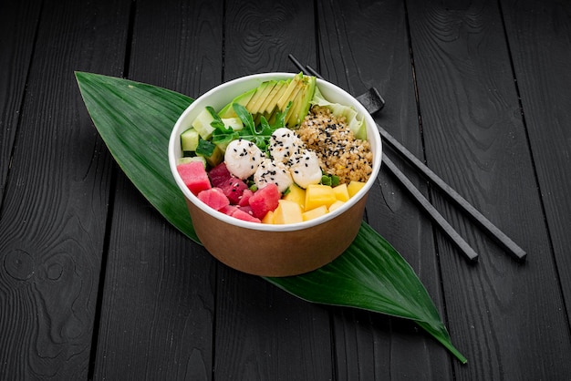 Poke bowl with tuna rice avocado cucumber cream cheese and mango on dark background