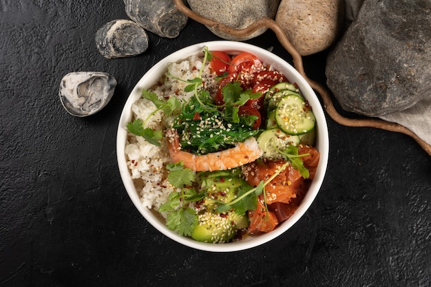 Poke with salmon, tiger shrimp and vegetables. A traditional Asian hot dish of seafood, boiled rice, avocado, cucumber, tomatoes and herbs