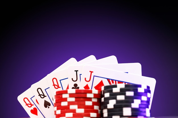 Poker chips and playing cards on black surface