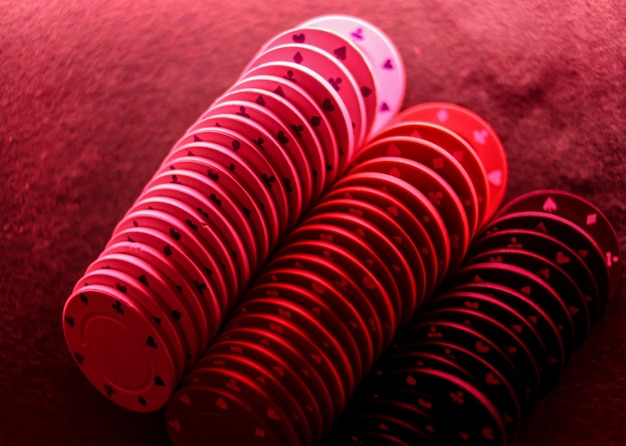 Poker game concept. Casino concept. Stack of poker chips in red light on the game poker table.