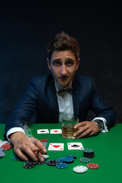 Poker player with cards and chips at green table in casino