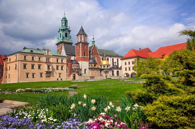 Poland. Krakow. Wawel Castle. Blooming park and domes of the cathedral against a cloudy sky