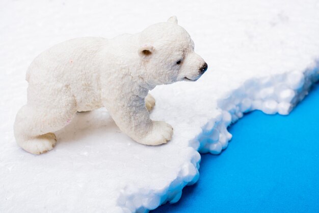 Polar bear cub model placed on fake snow and sea background environment