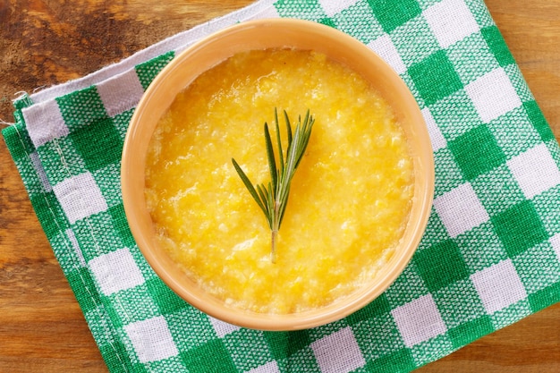 Polenta in ceramic bowl on rustic wooden table Cream of corn or mamaliga