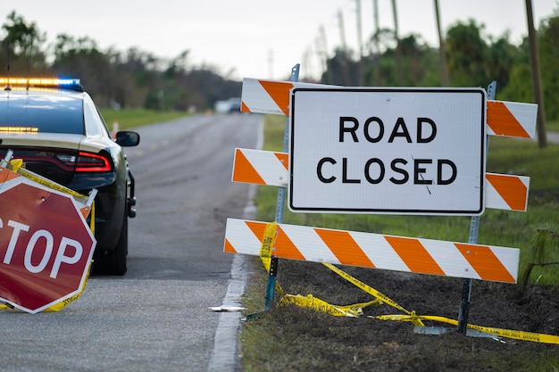 Police patrol car at warning roadworks sign and safety barrier on city street during maintenance repair work