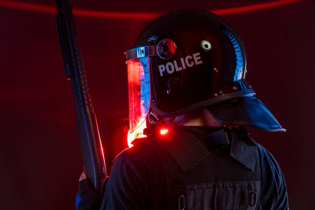 policeman with full equipment for anti-riot, Law enforcer in protective uniform ready for crowd control isolated on black