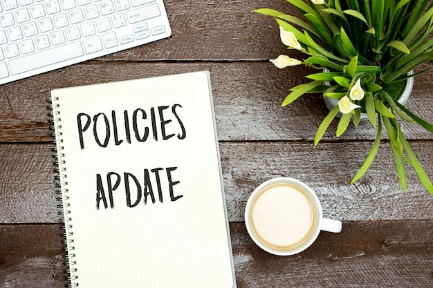 Policies Update text written on a notebook with keyboard and cup of milk coffee