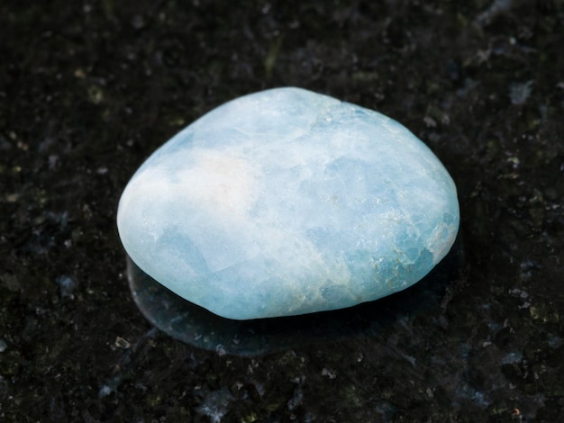 Polished aquamarine blue beryl gem stone on dark