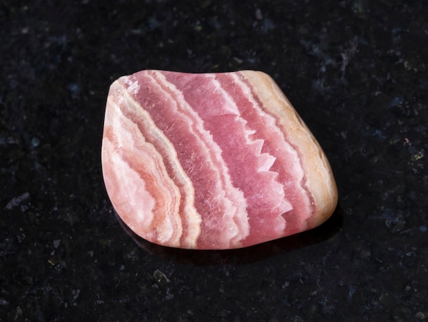 Polished rhodochrosite gem stone on dark