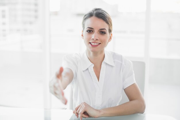 Polite young businesswoman reaching her hand to camera