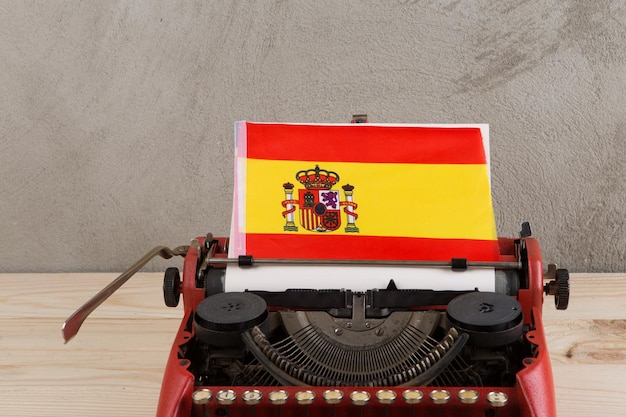 Political news and education concept red typewriter flag of the Spain on table on gray background