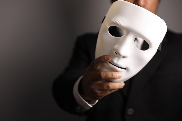 Politician or businessman wearing black suit and showing white mask 