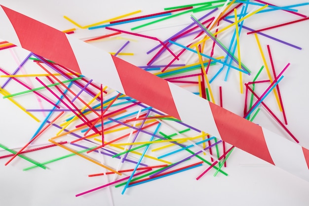 Polluted live. Colorful bright bunch of straws lying on the floor and crossed with red and white line