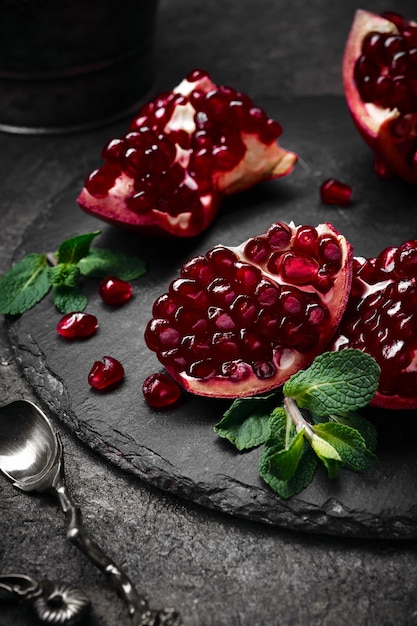 pomegranate berries, mint and retro spoons on black plate