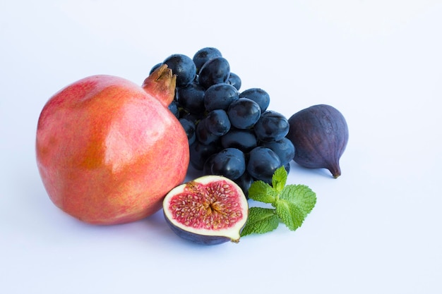 Pomegranate blue figs and grape on the white background Copy space Closeup