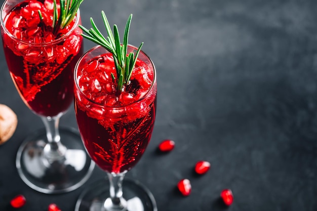 Pomegranate Champagne Cocktail with rosemary on gray concrete stone background copy space