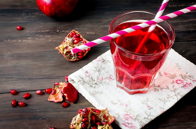 Pomegranate juice in glass and pomegranates  on dark old wooden background