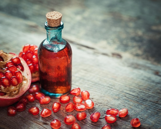 Pomegranate juice or tincture and garnet fruit with seeds on kitchen table