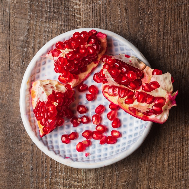 Pomegranate on a plate, flat lay, on wooden table.