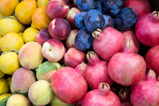 Pomegranate plums nectarines bunch peach at a showcase in a supermarket