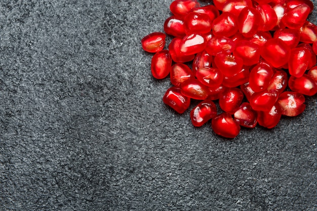 Pomegranate seeds on dark concrete table