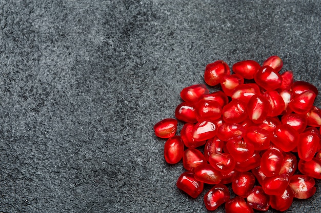 Pomegranate seeds on dark concrete table