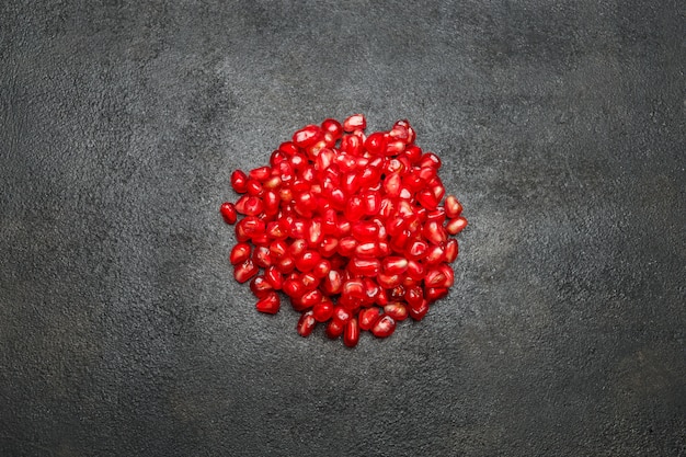 Pomegranate seeds on dark concrete table