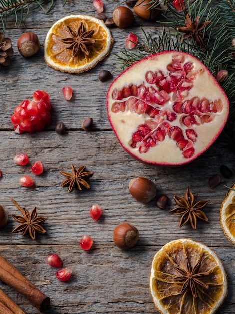 Pomegranate spruce branches star anise nuts, cinnamon and winter spices on wood