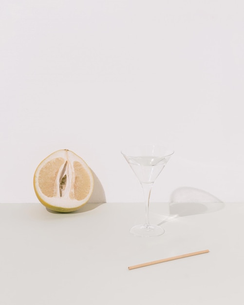 Pomelo cristal glass with liquid and bamboo stick on pastel green and white background