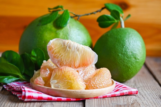 Pomelo fruit on wooden background fresh green pomelo peeled on plate and green leaf frome pomelo tree pummelo grapefruit in summer tropical fruit in thailand