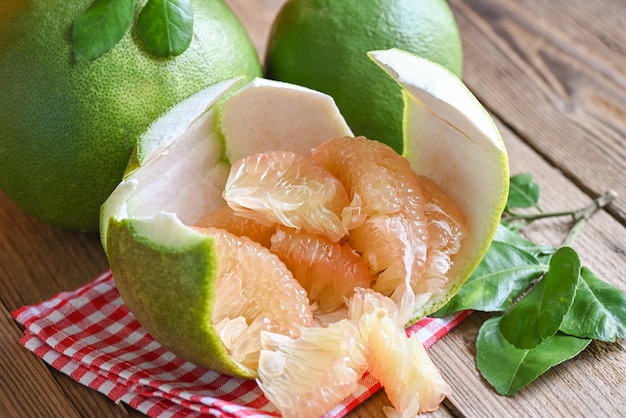 Pomelo fruit on wooden background fresh green pomelo peeled on pomelo skin and leaf frome pomelo tree pummelo grapefruit in summer tropical fruit in thailand