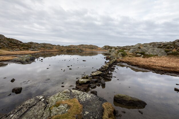 Pond by the trail, at the Rovaer archipelago, island in Haugesund, Norway. Stones making a path through the water.