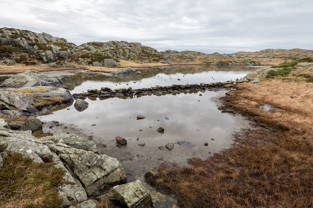 Pond by the trail, at the Rovaer archipelago, island in Haugesund, Norway. Stones making a path through the water.