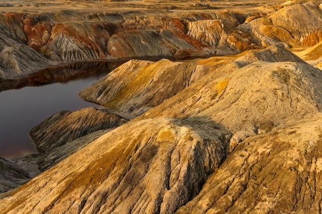 Photo a pond - a lake or a river - with red water in a canyon among deserted sandy hills