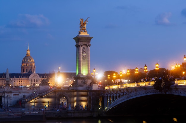 Pont Alexandre III Bridge and illuminated lamp posts at sunset with view of the Invalides 7th Arrondissement Paris France