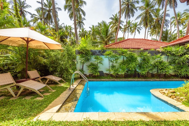 Pool with umbrella and beach beds in tropical hotel or house Idyllic scenic courtyard