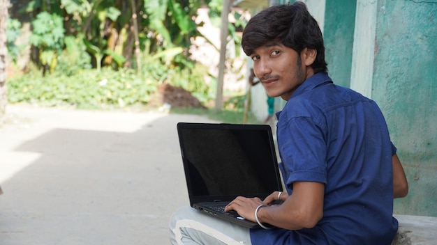 A poor boy with laptop attending class in village online class