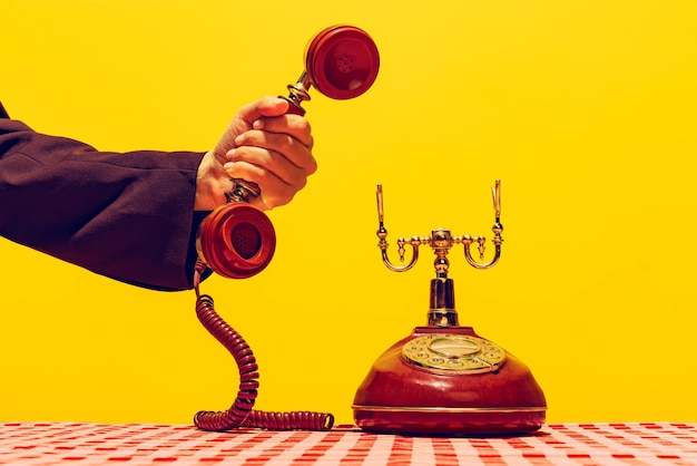 Pop art style Image of retro vintage telephone isolated over bright yellow background