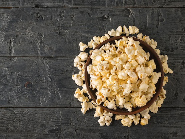 Popcorn is poured from a clay bowl on the table Place for your text