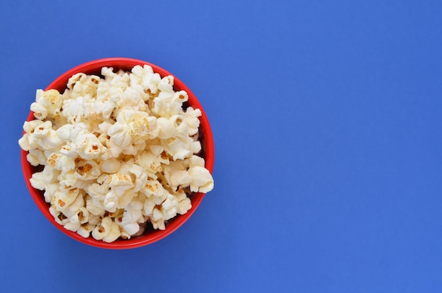 Popcorn in a red bucket on a blue background flat lay copy space