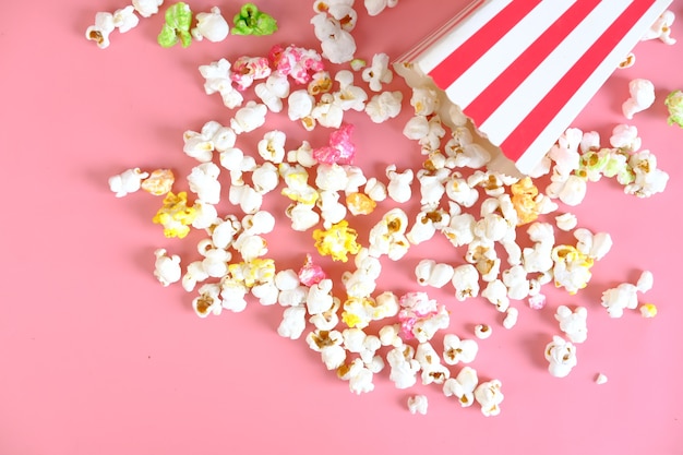 popcorn spilling from a container on pink