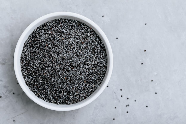 Poppy SeedsDry raw poppy seeds in bowl on gray stone background Top view copy space