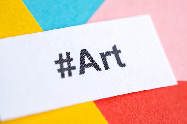 Popular hashtag 'art' printed on white sheet of paper on multicolored paper