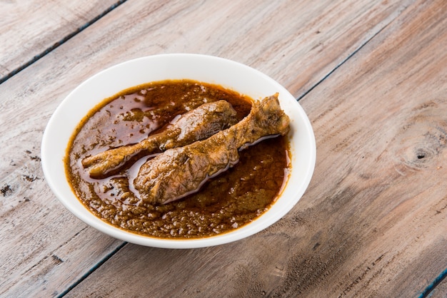 Popular reddish Chicken Curry or Masala, with prominent Leg Piece, served in a bowl