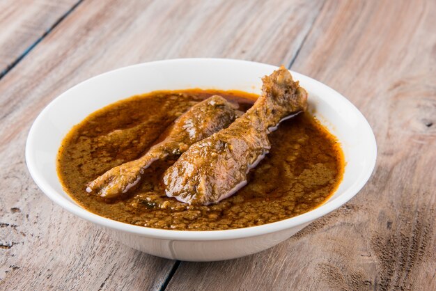 Popular reddish Chicken Curry or Masala, with prominent Leg Piece, served in a bowl