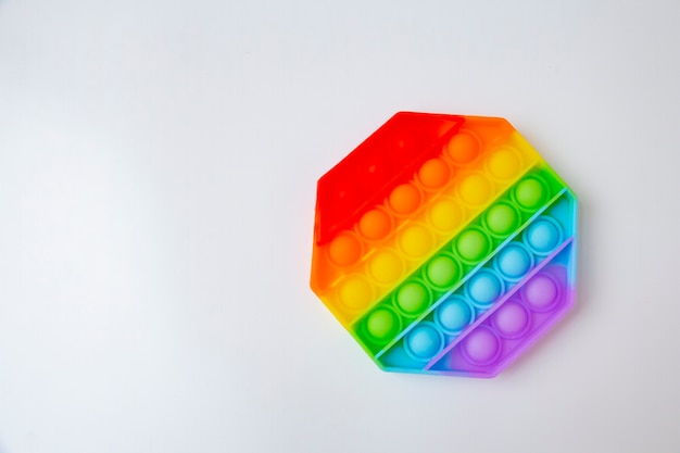 Popular silicone colorful anti-stress toy Pop It in the shape of a hexagon on a white surface.