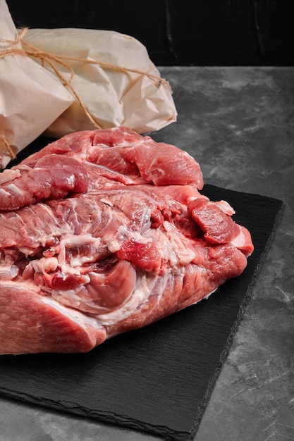 Pork ham, freshly meat on a slate plate on a gray background with vegetables.