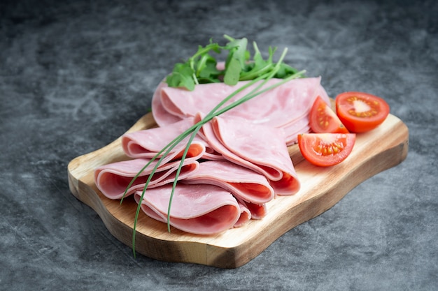 Pork ham slices on cutting board over dark background